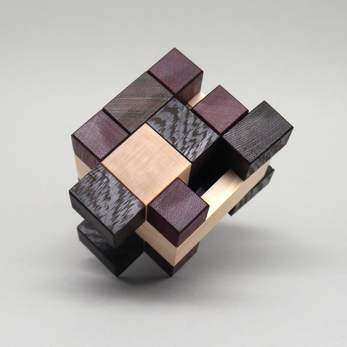 Holzpuzzle Denksport-Aufgabe in Würfelform mit verschiedenen Holzarten, zusammengesteckt zu einem komplexen IQ-Puzzle.