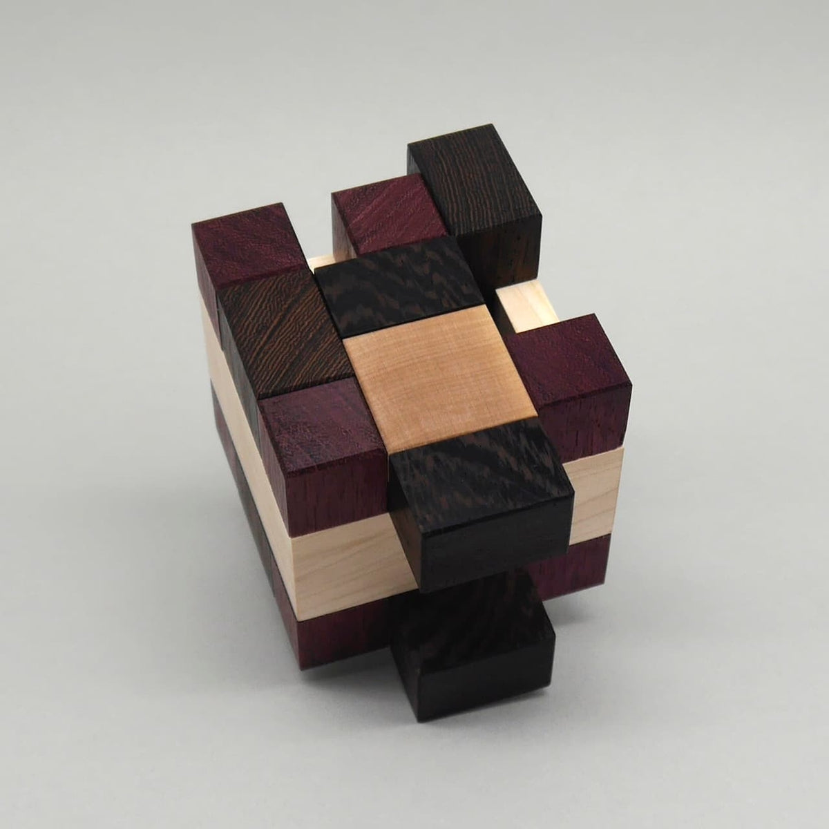 Geduldsspiel aus ineinandergreifenden Holzblöcken, ein interlocking Puzzle mit verschiedenen dunklen und hellen Hölzern.