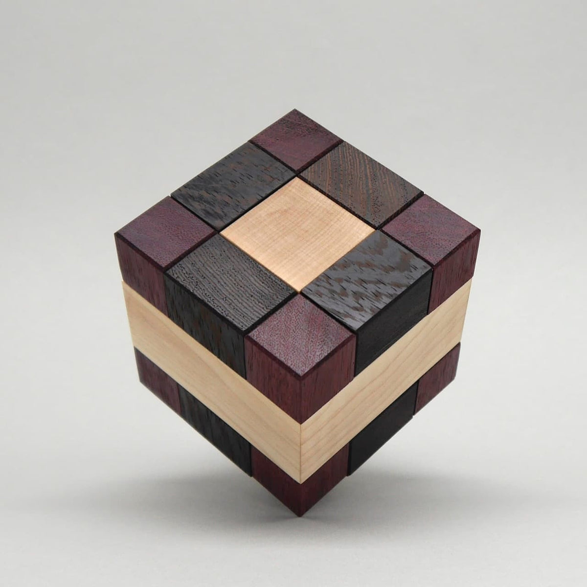 Holzwürfel Denkspiel aus mehreren farblich unterschiedlichen Holzarten, zusammengesetzt als präzises Wooden Puzzle.
