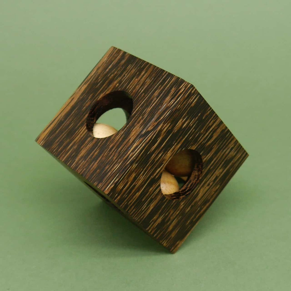 Auf eine Ecke gekippter Holzwürfel mit sichtbaren Kugeln in den Öffnungen – dekorative Puzzlebox zum Knobeln.