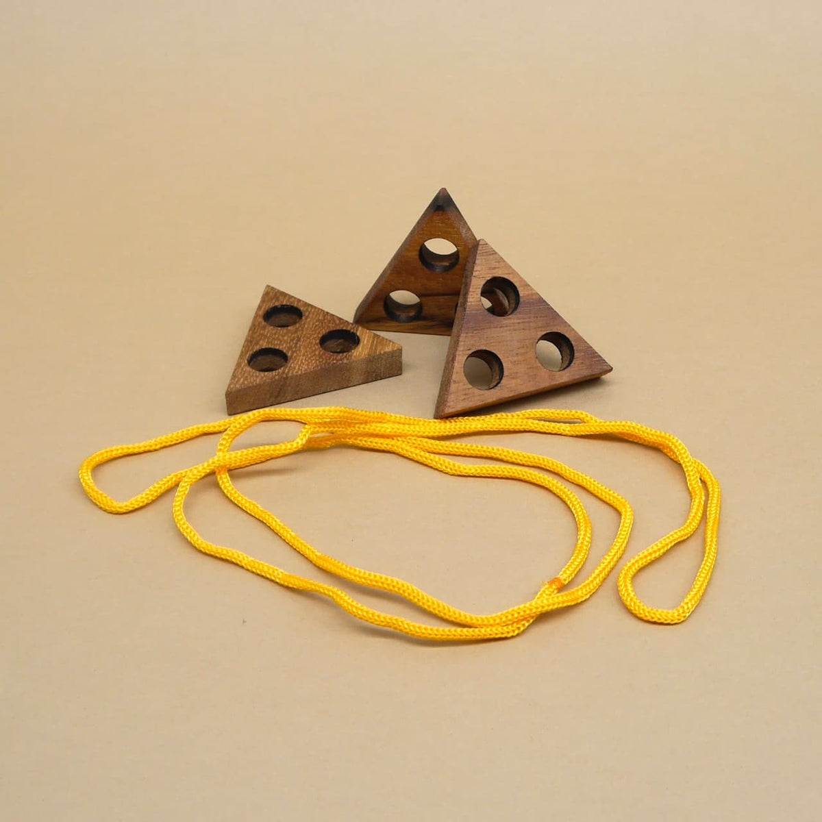 Holz-Knobelspiel mit gelbem Seil, bestehend aus drei durchbohrten Dreiecken – ideal für IQ-Training.