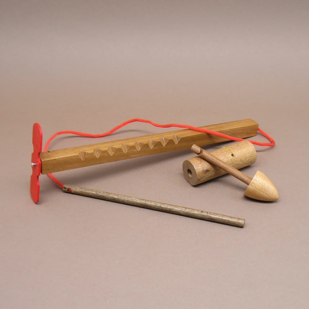 Knobelspiel aus Holz mit mehreren Bauteilen und roter Kordel als klassisches Geduldsspiel.