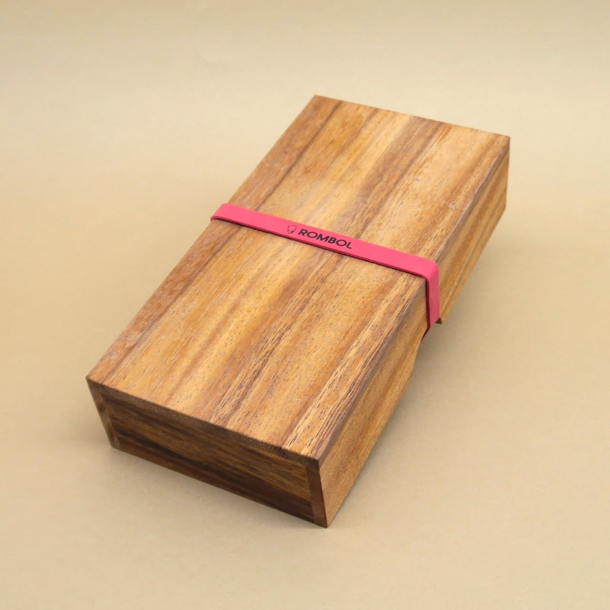 Geschlossene Holzbox mit pinkem Gummiband, ideal als stilvolles Legespiel für entspannte Spieleabende.