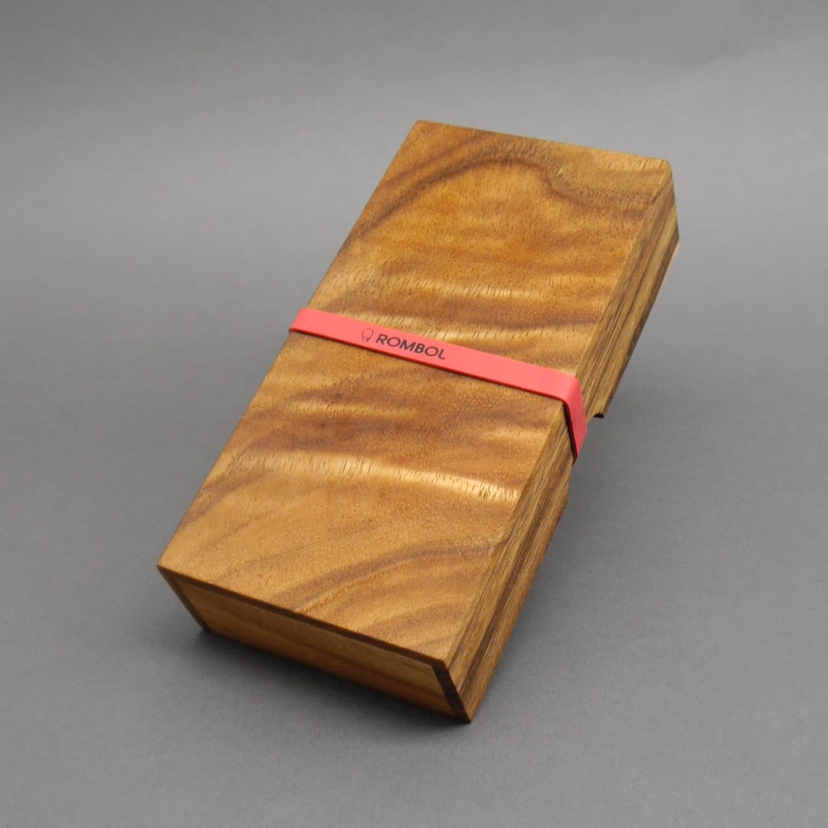 Rechteckige Holzbox mit dem klassischen Tridomino-Spiel, verschlossen mit einem roten Gummiband.