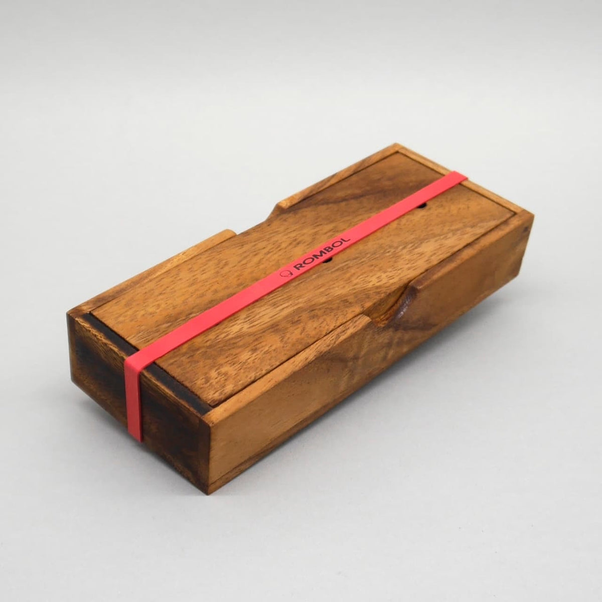 Kompakte Holzbox mit elastischem Band als Aufbewahrung für das Holzspiel ‚Turm von Hanoi‘.