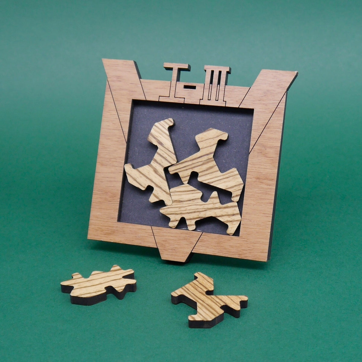 Holzrahmen mit eingelegten Puzzleformen in heller Maserung, zwei weitere Teile liegen davor – ein Logikspiel mit raffiniertem Design.