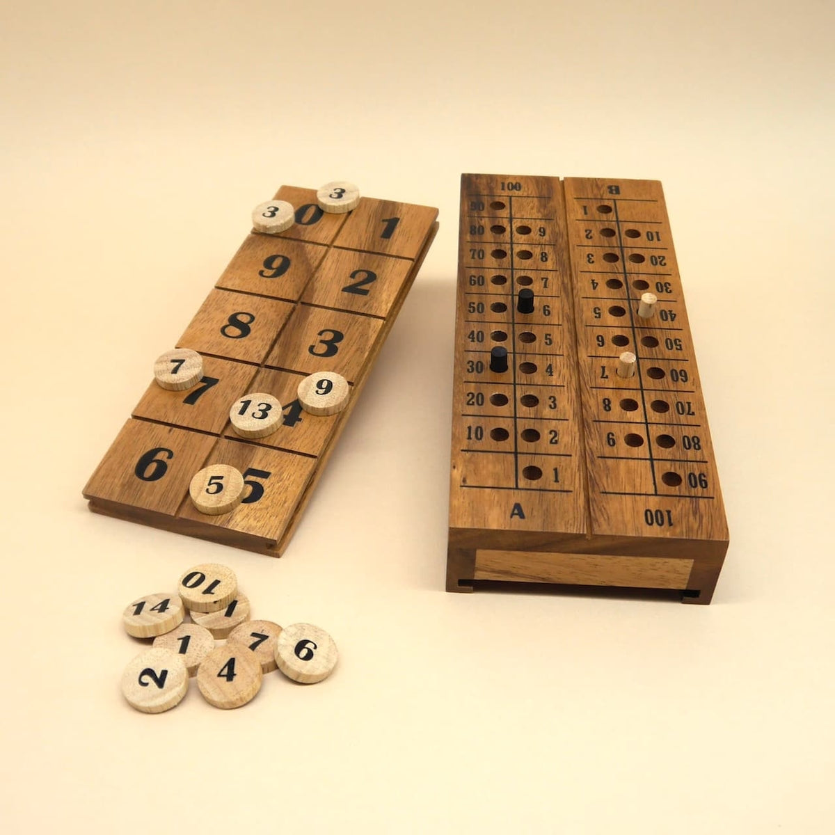 Brettspiel aus Holz mit nummerierter Klappbox und Loch-Zählleiste; mehrere runde Spielsteine liegen lose daneben auf hellem Hintergrund.