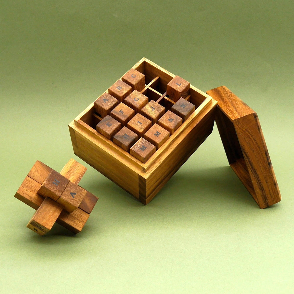 151er Teufelsknoten Denkspiele-Set: offene Holzbox mit beschrifteten Würfeln im Fachraster, davor ein Puzzleteil aus Holz.