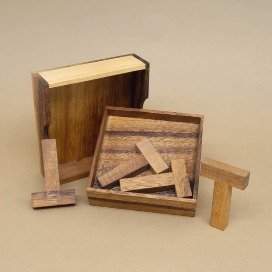 Geöffnete Holzschachtel mit mehreren T-förmigen Holzsteinen eines Legepuzzles, bereit zum Zusammensetzen.