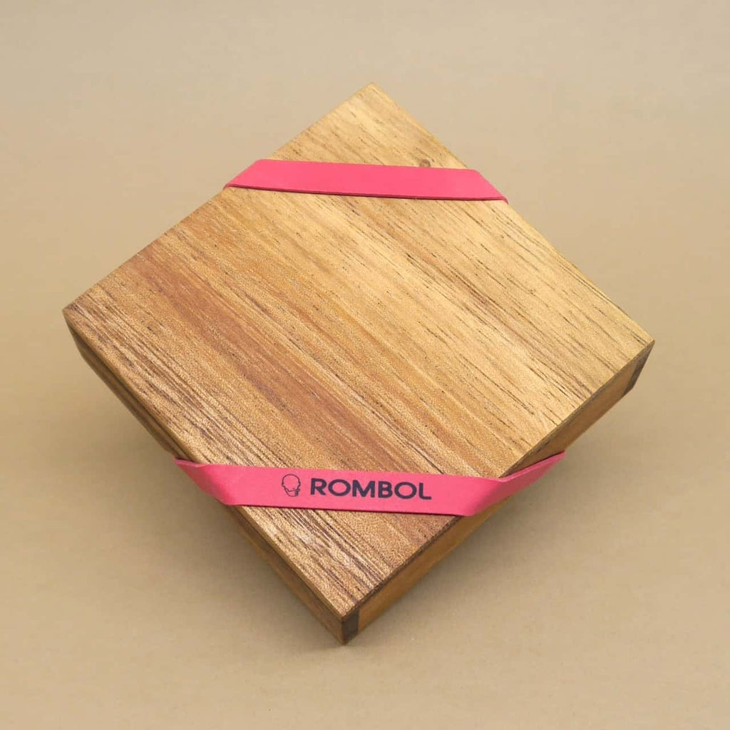 Quadratische Holzbox eines IQ-Puzzles, schräg aufgestellt und von einem rotem Band zusammengehalten.