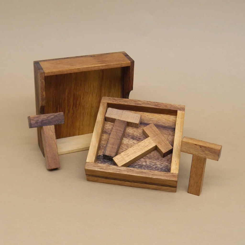 Offene Schachtel mit T-förmigen Teilen; das Holzpuzzle zeigt einige bereits eingelegte Elemente.
