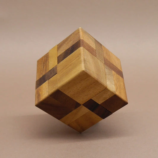 Denkspiel: vollständig zusammengesetzter Holzwürfel balanciert auf einer Ecke und zeigt kontrastreiche Maserungen.