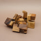 Holzwuerfel: lose verstreute Puzzleteile aus unterschiedlich gemasertem Holz liegen ungeordnet auf dem Tisch.
