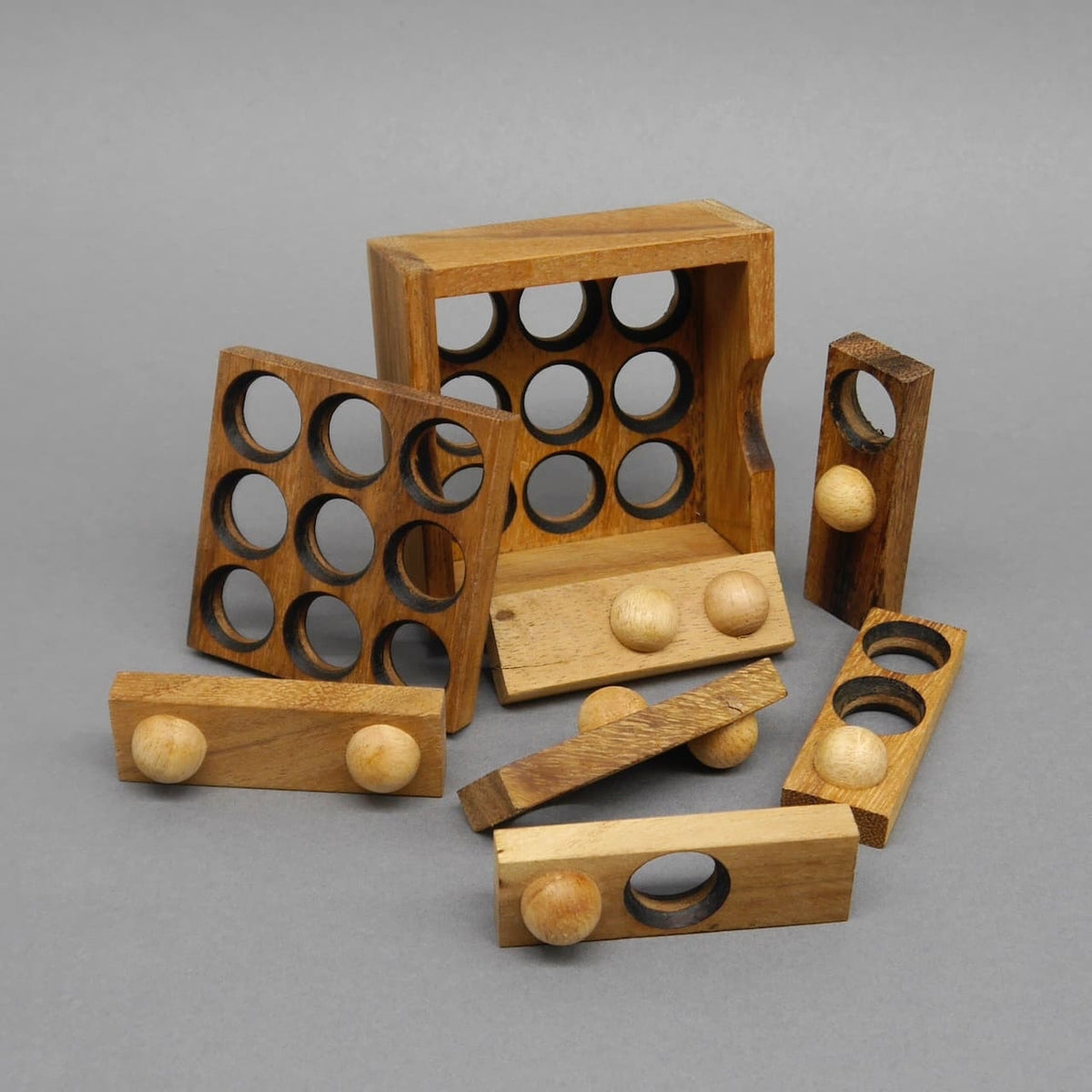 Alle Holzteile des 9‑Loch‑Puzzles verstreut vor der Box; ideale Geschenkidee für Liebhaber kniffliger Spiele.