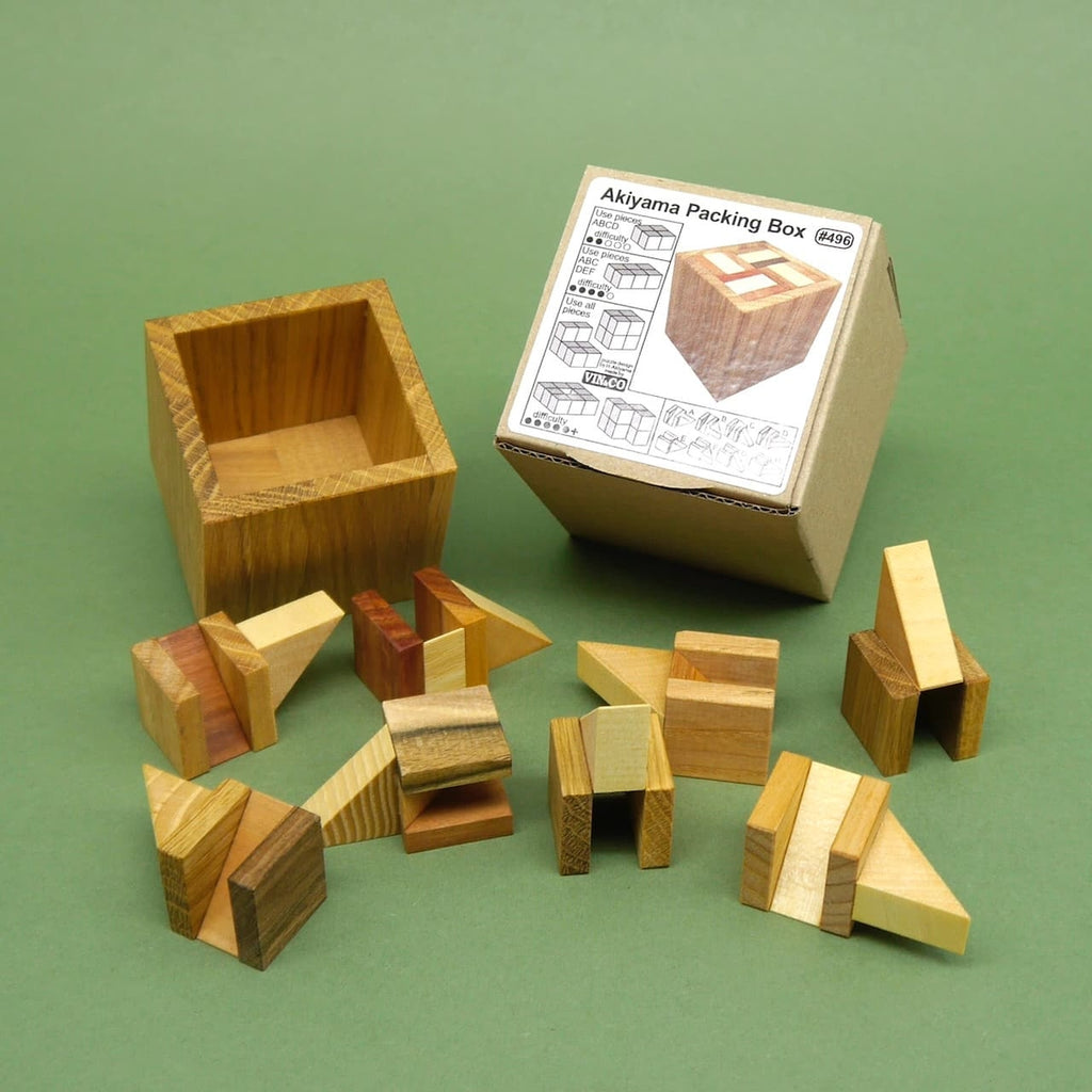 Offene Packing Box mit Holzwürfel-Teilen vor der Produktverpackung auf grünem Hintergrund.