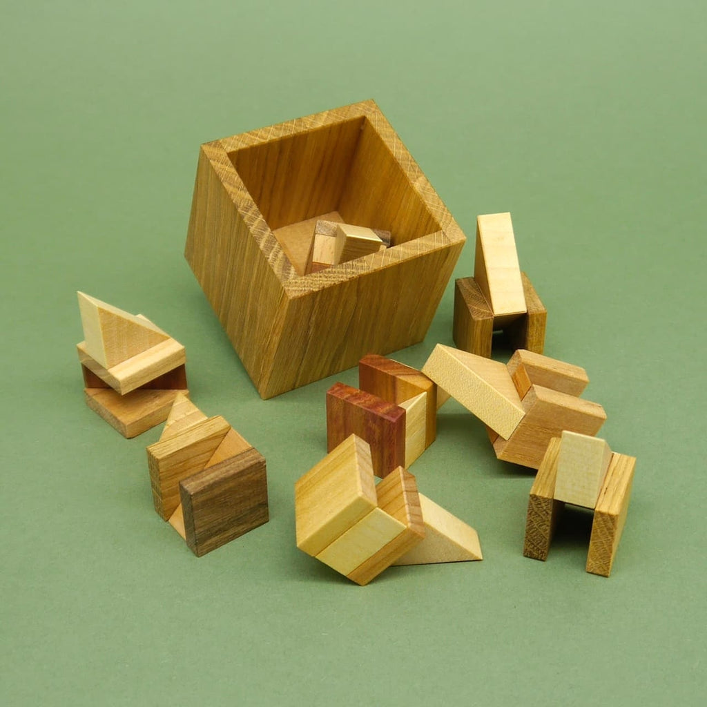 Zahlreiche Einzelteile des Holzpuzzles liegen neben der leeren Box bereit zum Zusammenbauen.