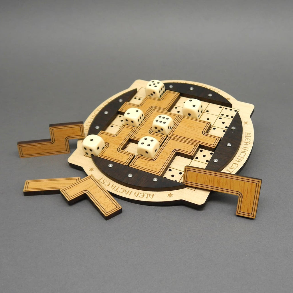 Holzpuzzle mit Würfeln und Tetris-ähnlichen Spielsteinen auf rundem Spielbrett mit Gravur „ALEA IACTA EST“, teilweise gelöst.