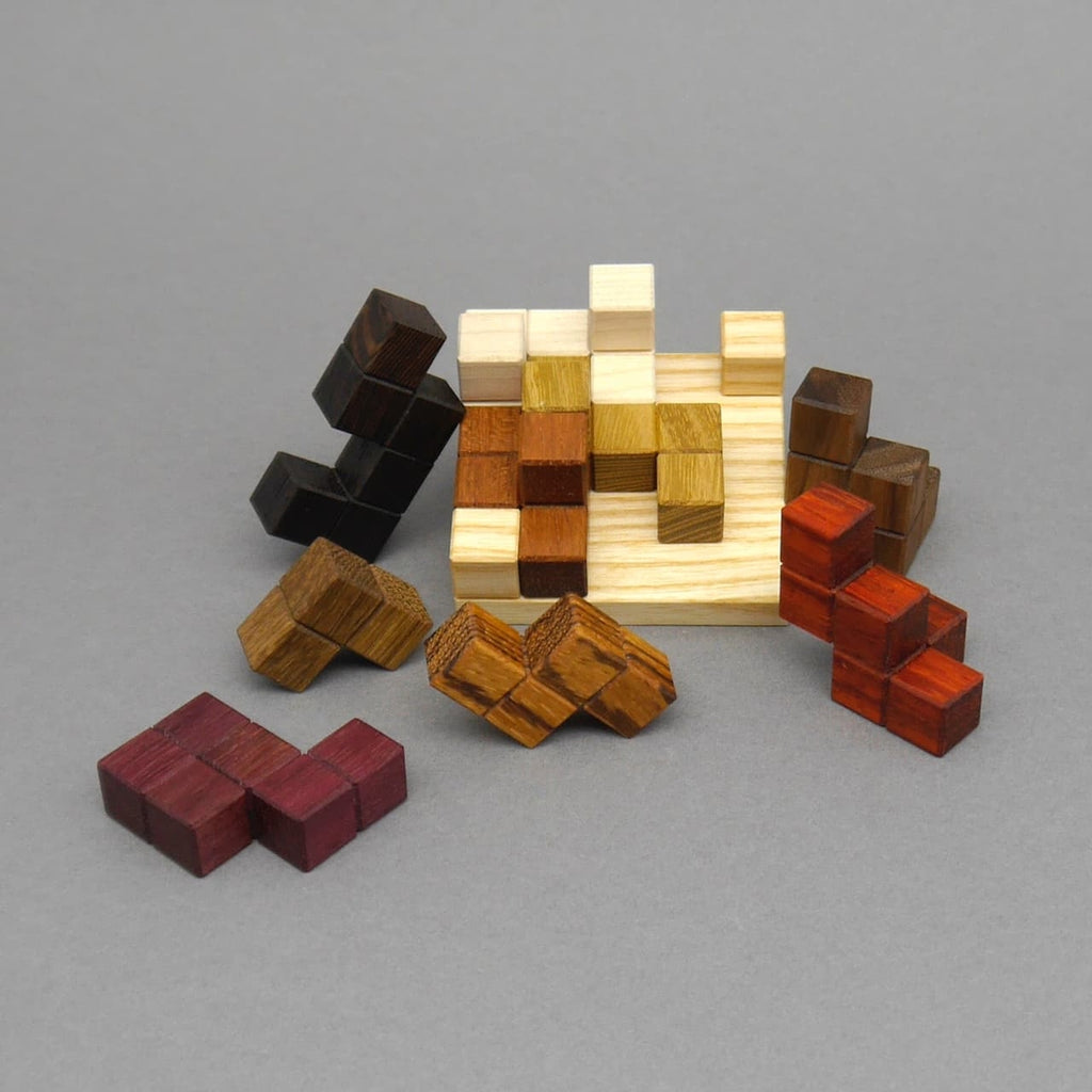 Farbiges Holz-Denkspiel mit mehreren zusammengesetzten Würfelelementen auf grauem Hintergrund.