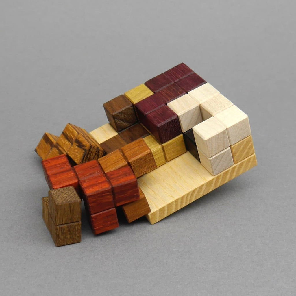 Teilweise eingelegtes Packpuzzle aus verschiedenfarbigen Holzsteinen auf einer Holzplatte.