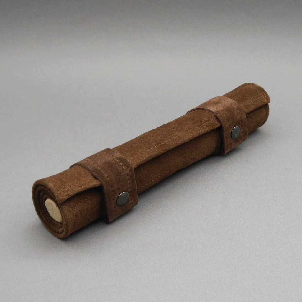 Zusammengerolltes Backgammon Gesellschaftsspiel aus braunem Wildleder, verschlossen mit zwei Riemen und Druckknöpfen.