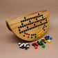 Großes halbrundes Holzbrett mit bunten Spielsteinen – kreatives Gesellschaftsspiel mit Würfeln und Farben.“