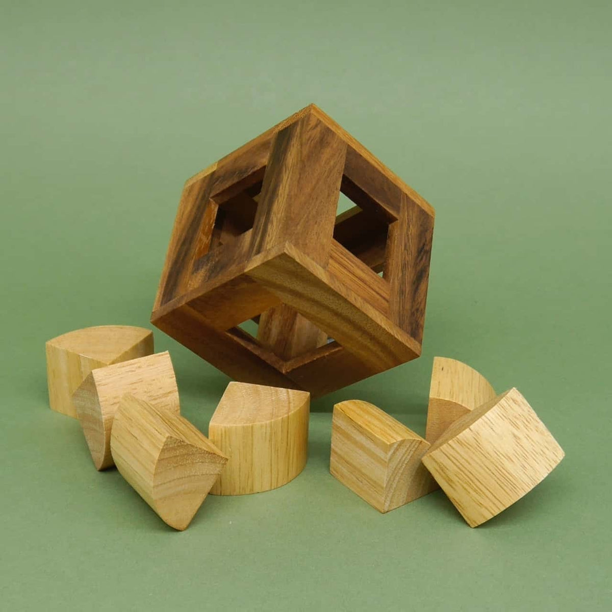 Knobelbox: Zerlegter Holz-Würfelrahmen samt halbkreisförmigen Rätsel-Bausteinen auf grünem Untergrund.
