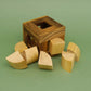 3D-Puzzle: Holz-Pack-Puzzle zum Knobeln, quadratischer Rahmen umgeben von losen gebogenen und würfelförmigen Teilen.