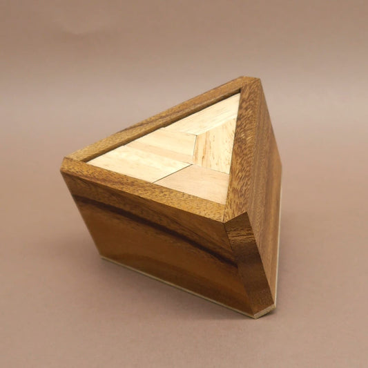 Seitlich fotografiertes, vollständig zusammengesetztes Bermuda-Dreieck Knobelpuzzle aus verschiedenfarbigen Holzsegmenten.