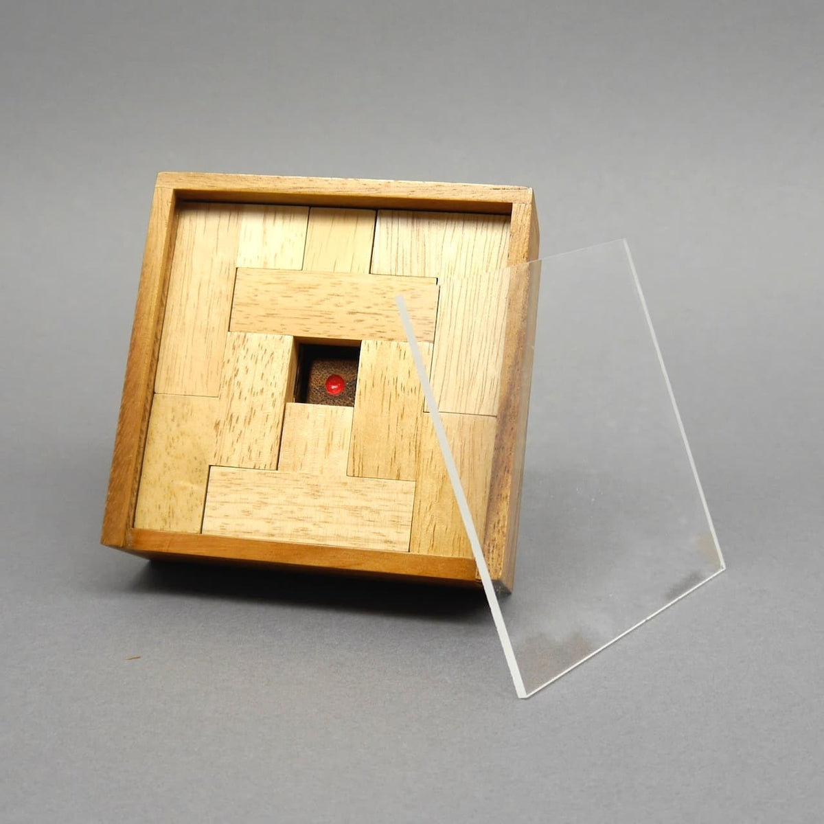 Fertig zusammengesetztes Würfelspiel in quadratischer Holzbox, daneben schräg angesetzte Acrylglasplatte als Deckel.