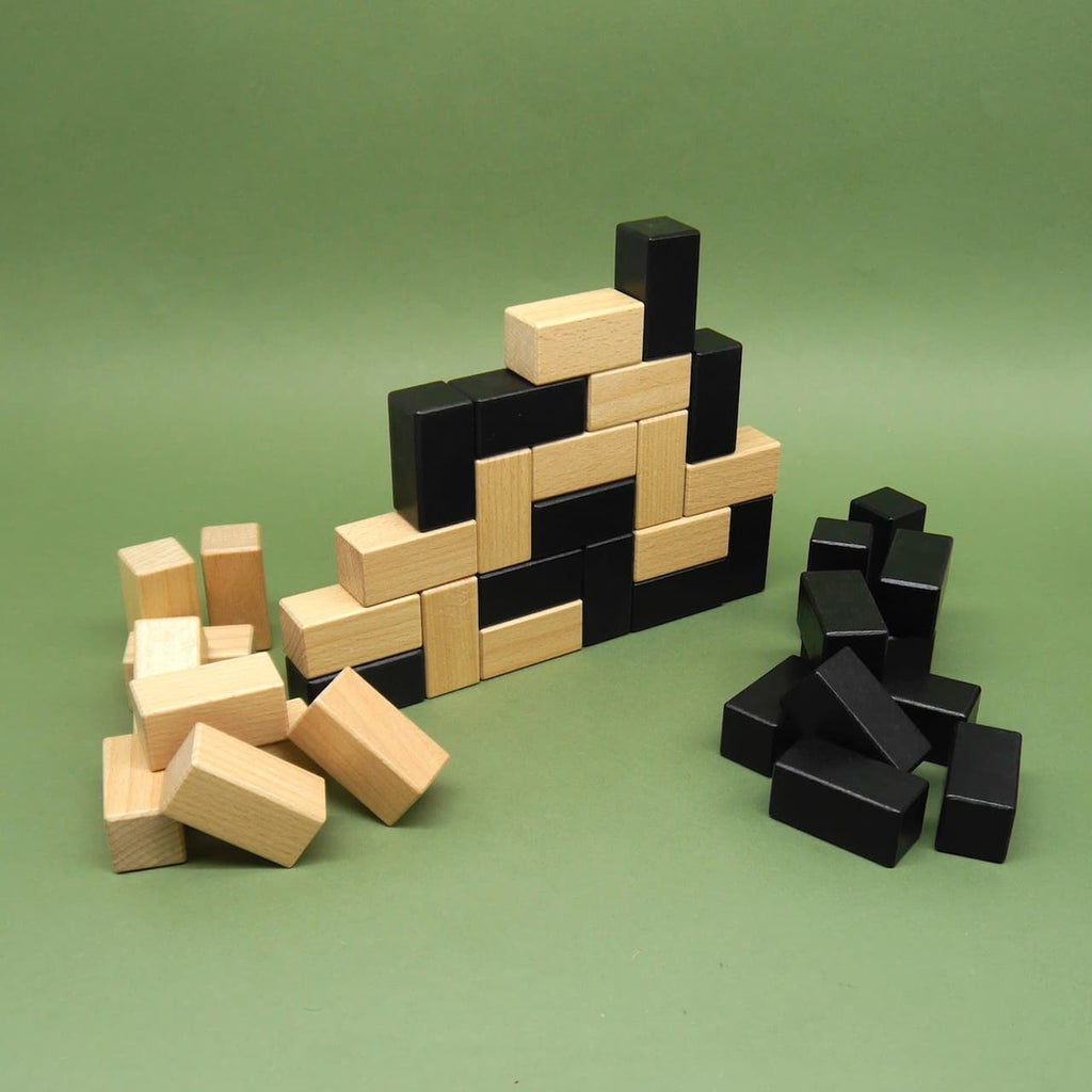 Halb aufgebautes Holzspiel mit schwarzen und naturfarbenen Bausteinen – ein anspruchsvolles Taktikspiel aus Holz.