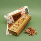 Das kompakte Holzspiel „Borkums 6“ samt weiß-roter Verpackung, Spielbrett mit eingesetzten Stiften und verstreuten Holzspielsteinen ist übersichtlich vor grünem Hintergrund arrangiert.