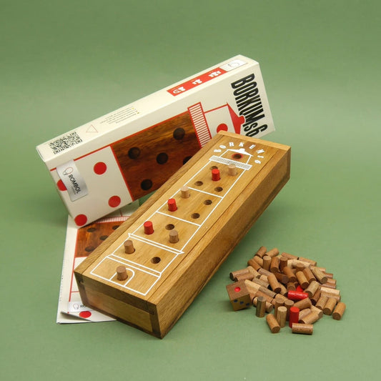 Das kompakte Holzspiel „Borkums 6“ samt weiß-roter Verpackung, Spielbrett mit eingesetzten Stiften und verstreuten Holzspielsteinen ist übersichtlich vor grünem Hintergrund arrangiert.