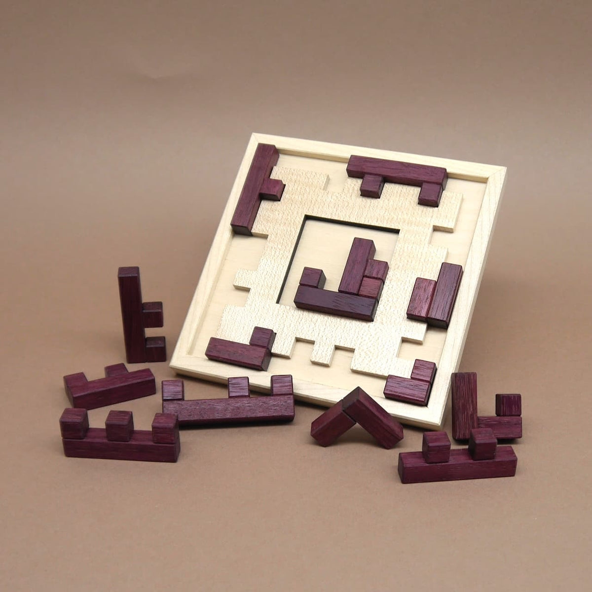 Unvollständig gelöstes Holzpuzzle „Broken Frame and Window“ mit lila Spielsteinen um den hellen Holzrahmen verteilt.