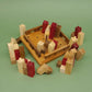 Naturfarbene und rote Holztürme säumen eine teilbestückte Basisplatte; das Castle-Puzzle zeigt seine Burgteile locker um das Spielfeld verteilt.