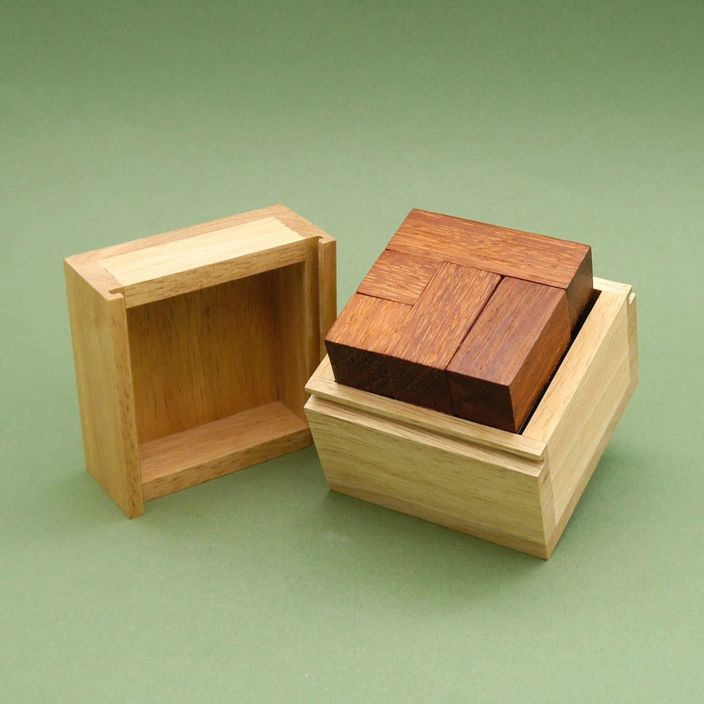 Geöffnete Cabrio Holzpuzzle-Box mit passgenauen dunklen Holzteilen im Inneren, auf grünem Hintergrund.
