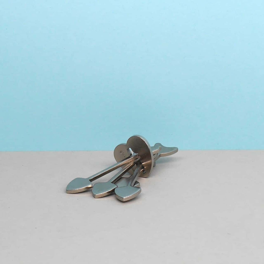 Detailansicht des zerlegten Metallpuzzles Cast Arrows mit vier Pfeil-Segmenten vor runder Scheibe.