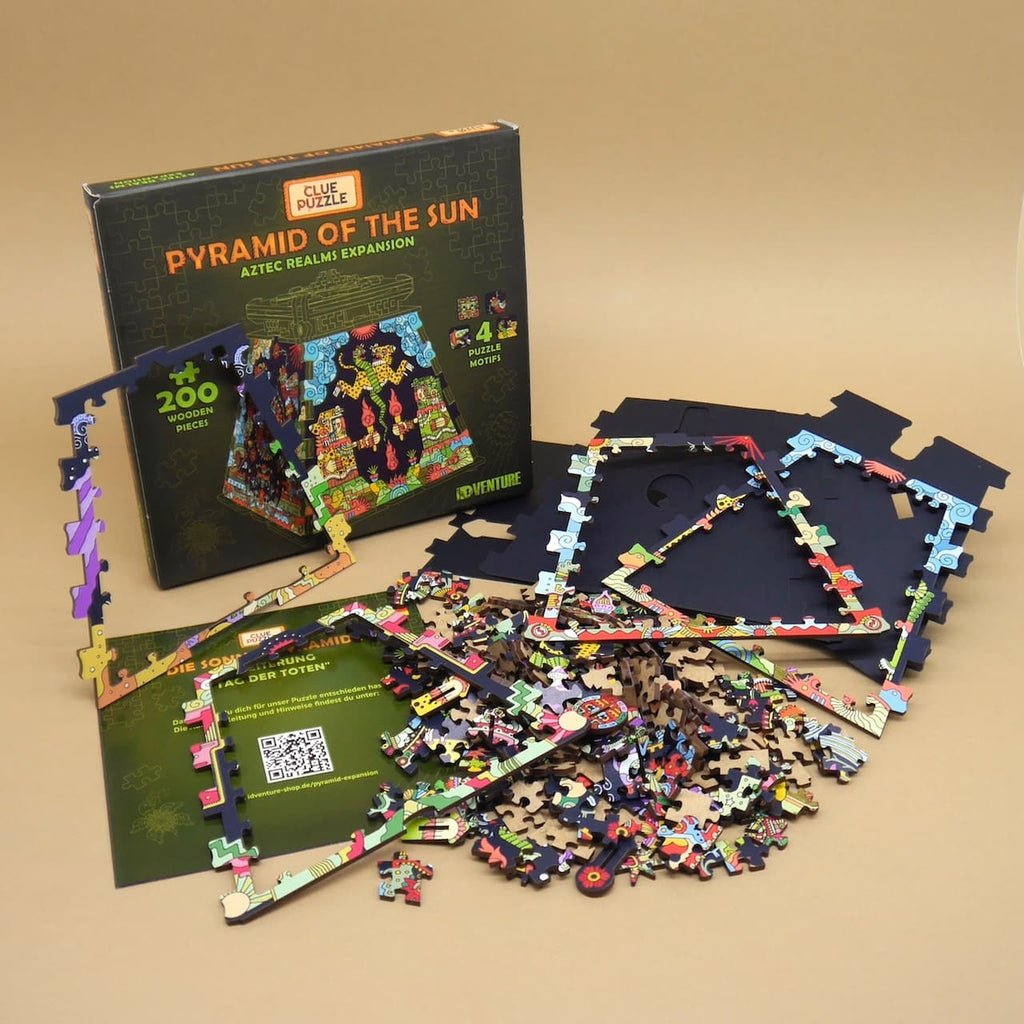 Pyramid of the Sun Holzpuzzle: Box, Rahmenplatten und bunte Teile der Aztec Realms Expansion ausgebreitet auf beigem Hintergrund.