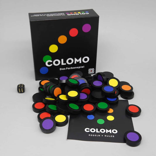 COLOMO Kinderspiel: offene Schachtel, Regelheft und viele farbig bedruckte Spielsteine liegen ausgebreitet.