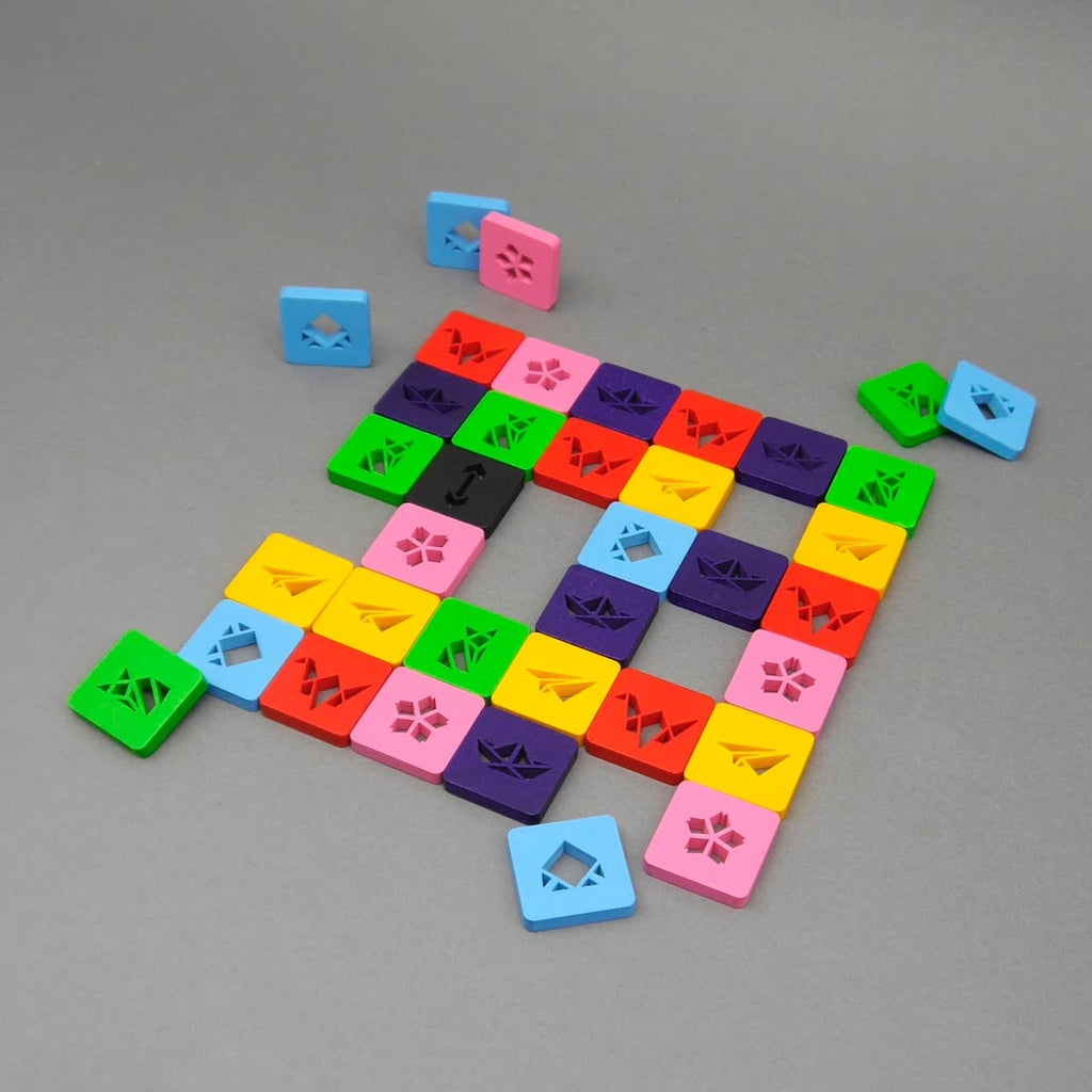 Farbspiel Coloro mit vielfarbigen quadratischen Spielsteinen, die ein Raster auf grauem Hintergrund bilden.