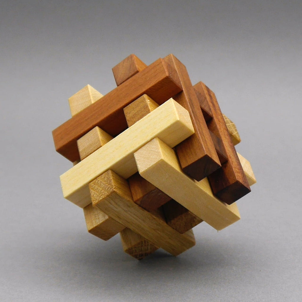 Holz-Interlocking Denkspiel vollständig zusammengesetzt; mehrfarbige Leisten bilden einen kompakten Würfel auf grauem Hintergrund.