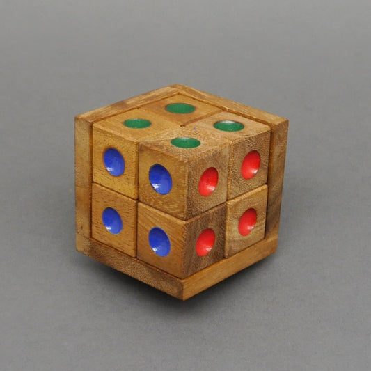 Farbpuzzle-Holzwürfel, komplett zusammengesetzt – sechs kleine Würfel mit grünen, blauen und roten Farbpunkten bilden einen großen Würfel vor grauem Hintergrund.