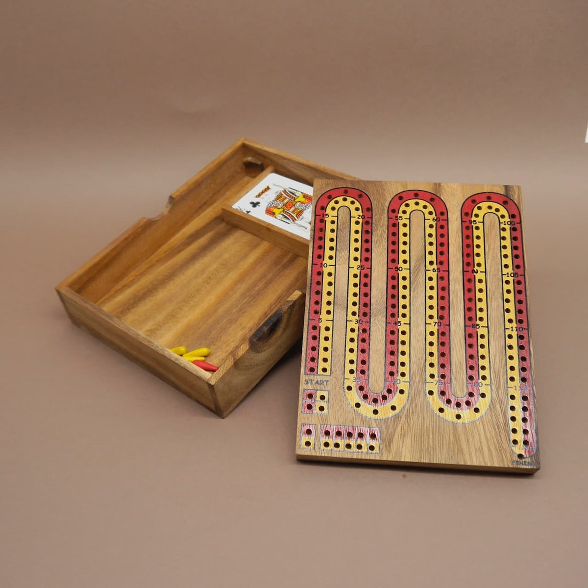 Offene Holzkiste mit einem Cribbage-Brettspiel, Spielkarten und bunten Spielstiften – ideal für gemütliche Familienspiele