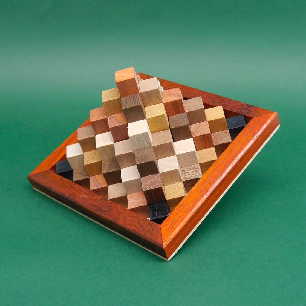 Seitenansicht der aufgebauten Holzpyramide aus kleinen Holzwürfeln in einem dekorativen Holzrahmen.