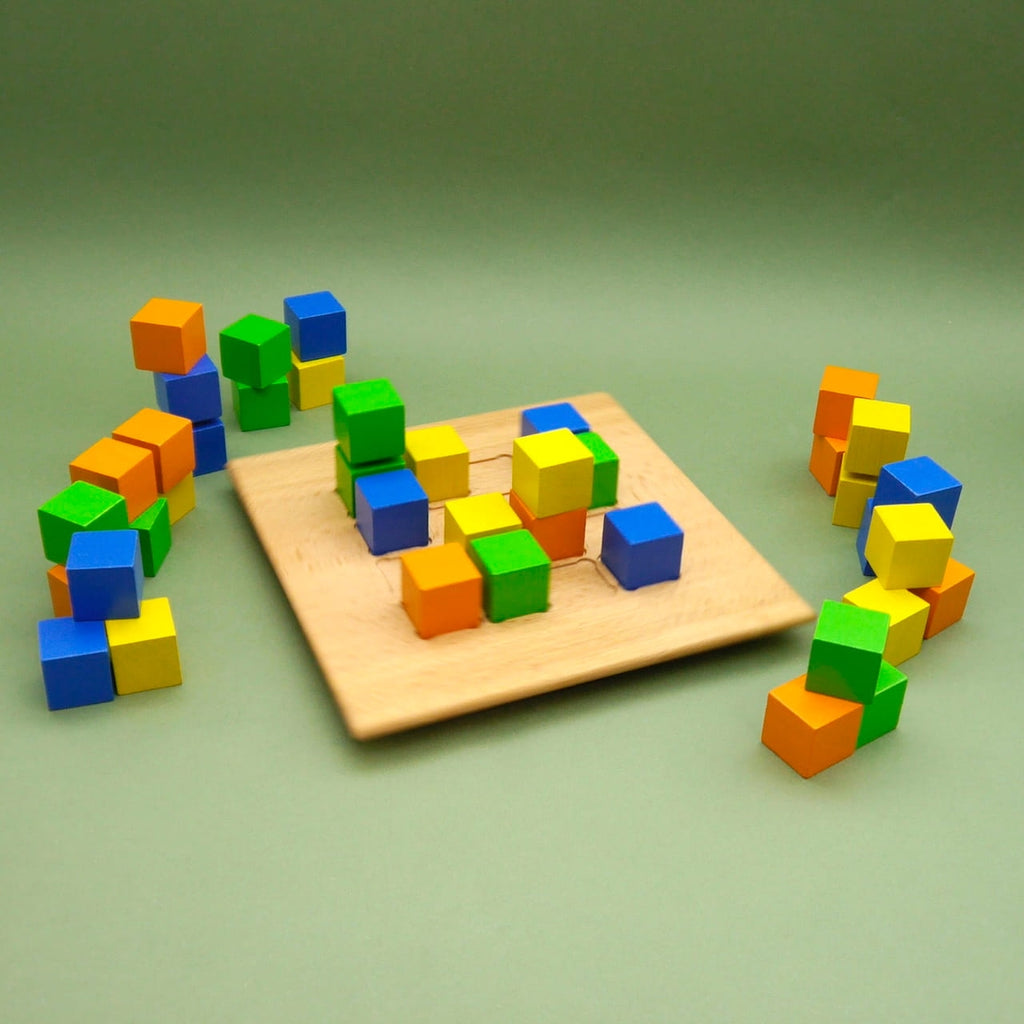 Montessori-inspiriertes CUBE Spiel: Holzbrett mit farbigen Würfeln, freie Anordnung zum räumlichen Denken.