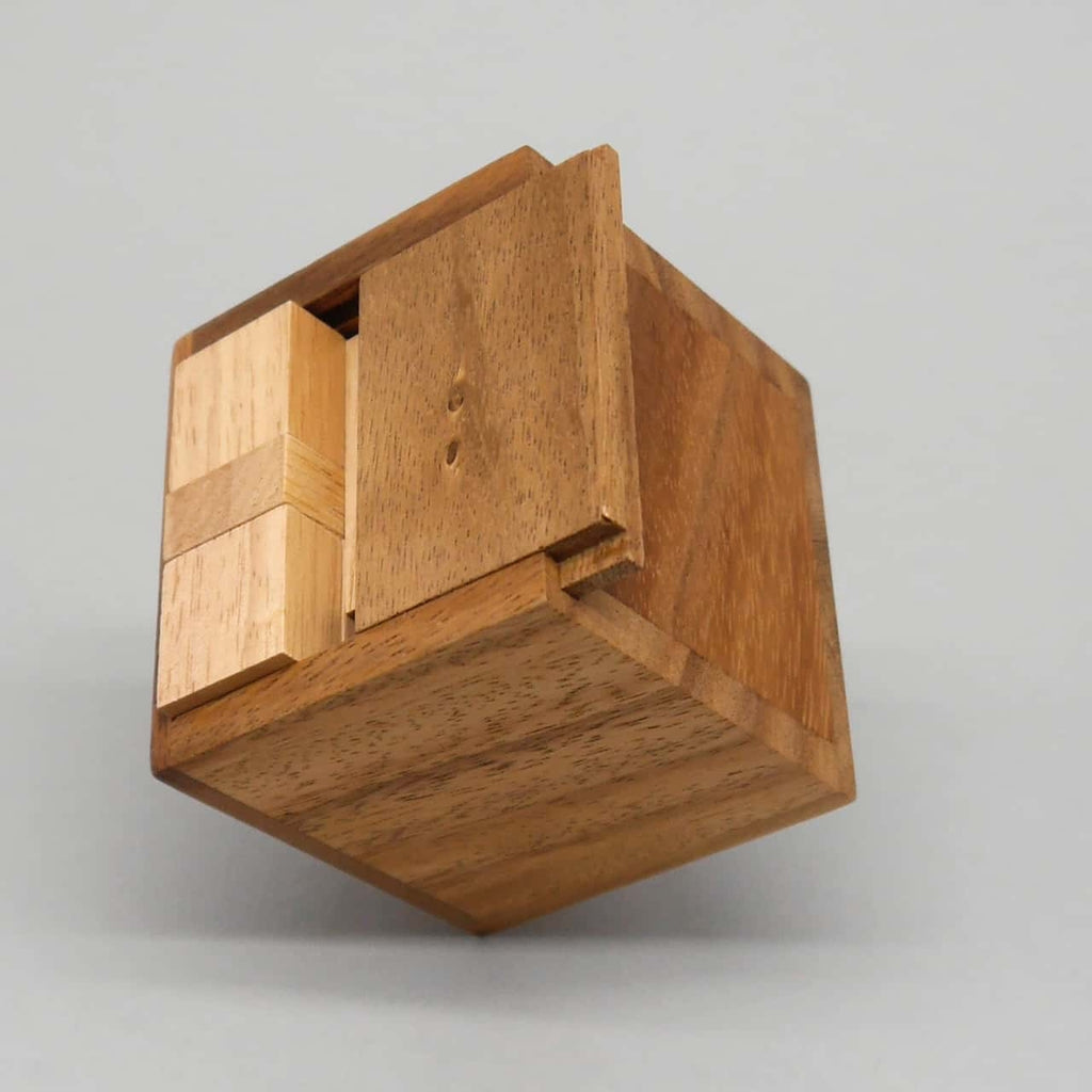 Geschlossener Holz­würfel mit verschiebbarer Frontplatte – minimalistisches Logikspiel als 3D-Geduldsspiel.