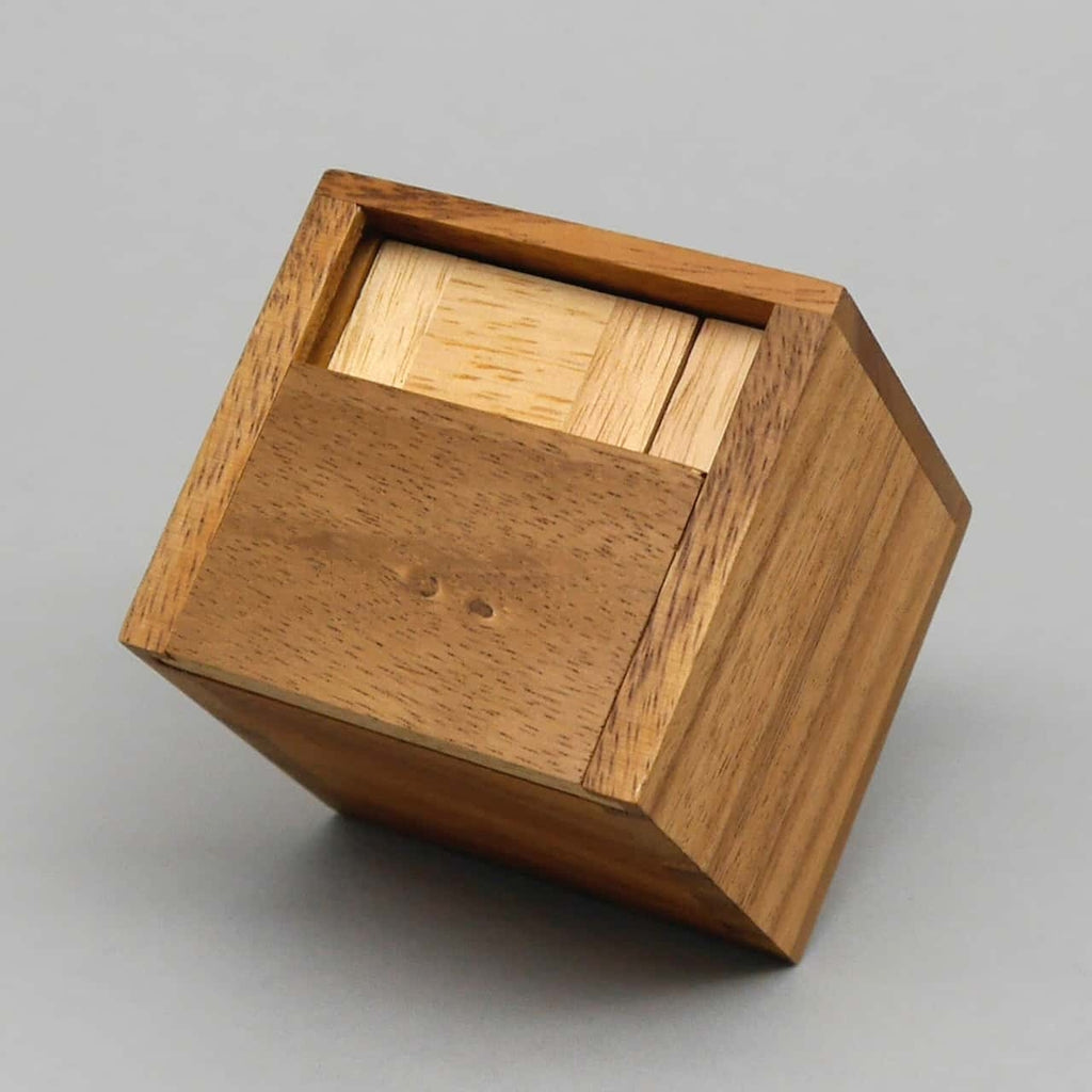 Würfelförmige Knobelbox aus zwei Holzarten, teils geöffnet, mit präziser Schiebemechanik.