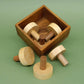 Offene Holzbox mit verstreuten zylindrischen Steckteilen eines Logikspiel-Puzzles auf grünem Untergrund.