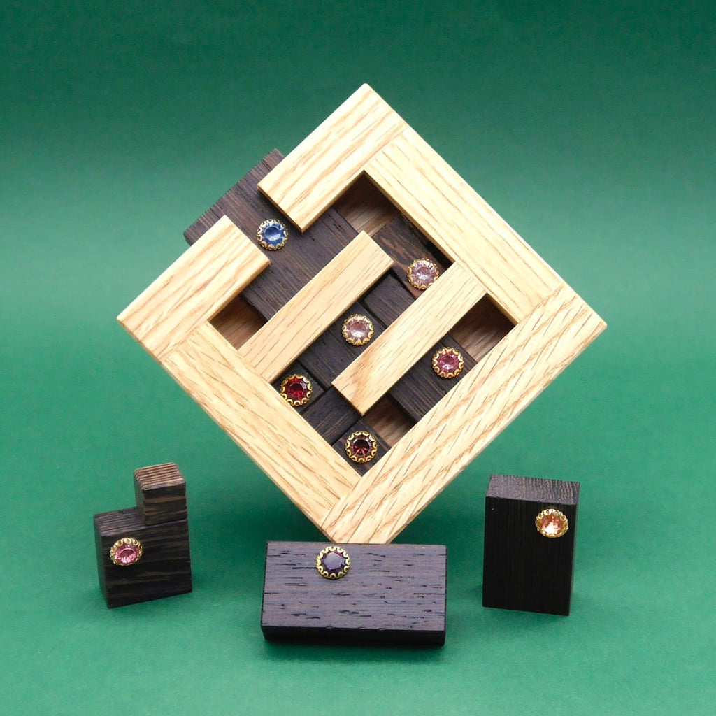 Diamantenpuzzle aus hellem und dunklem Holz, verziert mit kleinen Steinen, als kunstvoll angeordnetes 3D Puzzle auf grünem Hintergrund.