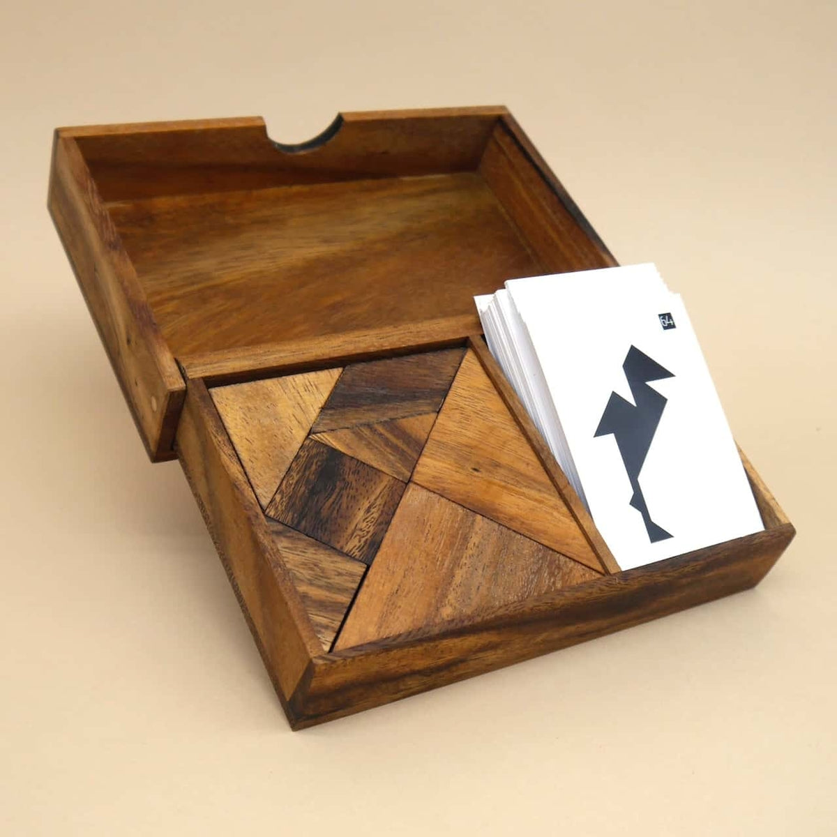 Vollständig zusammengesetztes Doppeltangram in Holzbox neben Karten – ein klassisches Geduldsspiel in edler Ausführung.