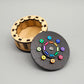 Geöffnete runde Knobelbox aus Holz mit farbigen Elementen auf dem Deckel – die kreative Kombination aus Puzzlebox und Geschenkbox.